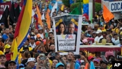 FILE - A supporter holds up a banner with images of opposition leader Maria Corina Machado and presidential candidate Edmundo Gonzalez during a campaign rally in Maracaibo, Venezuela, on May 2, 2024.