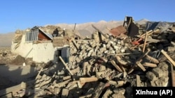 Warga berdiri di tengah rumah-rumah yang rusak akibat gempa bumi di Desa Tonglai, Kecamatan Changsuo, Dingri, Xigaze, Daerah Otonomi Tibet, China barat daya pada Selasa, 7 Januari 2025. (Xinhua via AP)