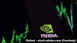 상승하는 주가 차트가 흐릿하게 보이는 배경 속에서 스마트폰 화면에 표시된 엔비디아(Nvidia) 로고.