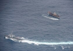 FILE - Ecuadorian Navy vessels surround a fishing boat after detecting a fishing fleet of mostly Chinese-flagged ships in an international corridor that borders the Galapagos Islands' exclusive economic zone, in the Pacific Ocean, August 7, 2020.