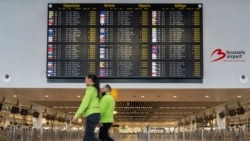 Dua pekerja bandara berjalan melewati tanda keberangkatan yang penuh dengan pembatalan selama aksi mogok nasional terhadap pemotongan anggaran federal di Brussels, Kamis, 13 Februari 2025. (Marius Burgelman/AP)