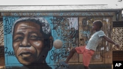 FILE - A child kicks a football in front of a mural of the country's first Black president and leader of the ruling African National Congress Nelson Mandela, in Soweto, South Africa, as the country celebrates Freedom Day, on April 27, 2024.