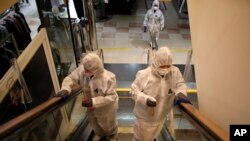 Workers wearing protective gear spray disinfectant as a precaution against the new coronavirus at a department store in Seoul, South Korea, March 2, 2020. 