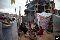 A Palestinian family cooks on fire next to their tent in an area largely destroyed by the Israeli army's air and ground offensive in Jabaliya, Gaza Strip, on Feb. 11, 2025.