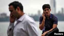 FILE - Men speak on their mobile phones on a seafront in Mumbai, Aug. 28, 2014.