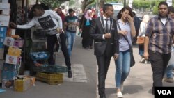 Young Egyptians pass by a kiosk near Ain Shams University in Cairo, April 21, 2016. College students in Egypt worry about jobs, as the country has long had more college graduates than jobs in desired professions. (H. Elrasam/VOA)