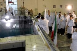 FILE - A handout picture released by Iranian President Mahmoud Ahmadinejad's official website shows him at right, listening to an expert during a tour of the Tehran Research Reactor, Feb. 15, 2012.