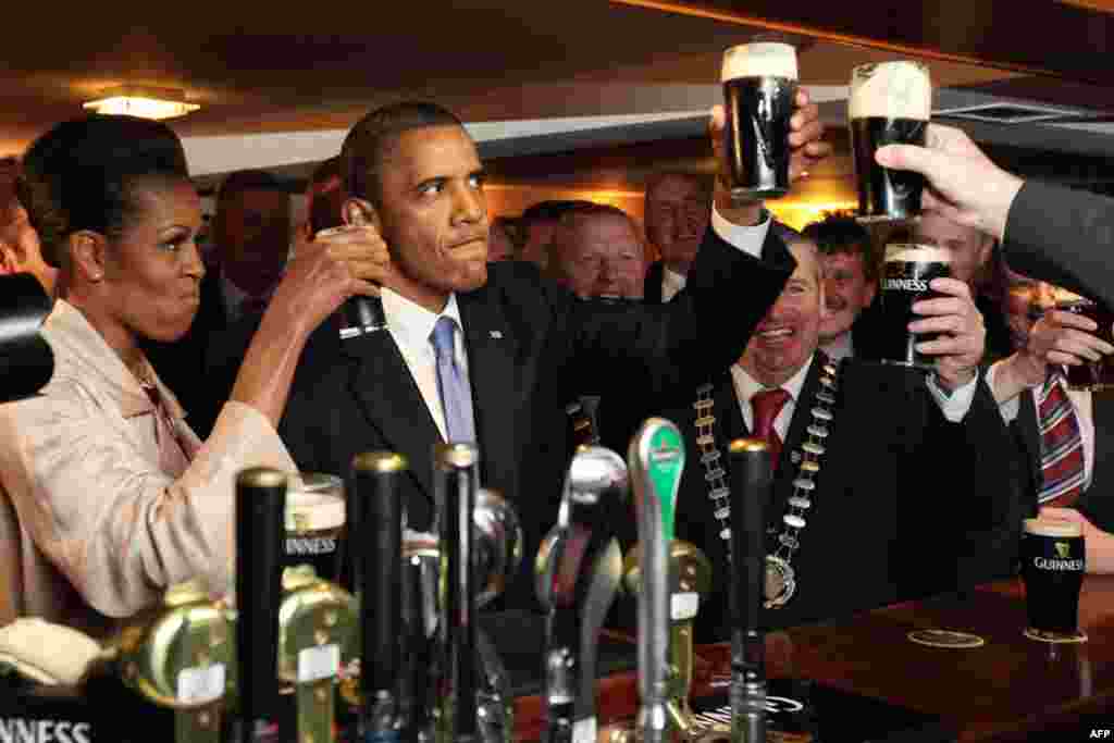 23/5: Tổng thống Obama và phu nhân thưởng thức bia Guinness trong lúc gặp người dân tại một quán bar ở thị trấn Moneygall, Ireland, nơi hai ông bà vừa đi thăm căn nhà của các bậc tiền bối của ông Obama. (AP Photo/Pool)