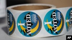 A roll of stickers sits on the table of an election judge for distribution to voters as they cast their ballots in the atrium of Ball Arena on Oct. 30, 2020, in Denver, Colorado. 