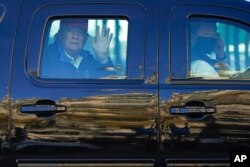 FILE - President Donald Trump waves to supporters from his motorcade as people gather for a march in Washington, Nov. 14, 2020.