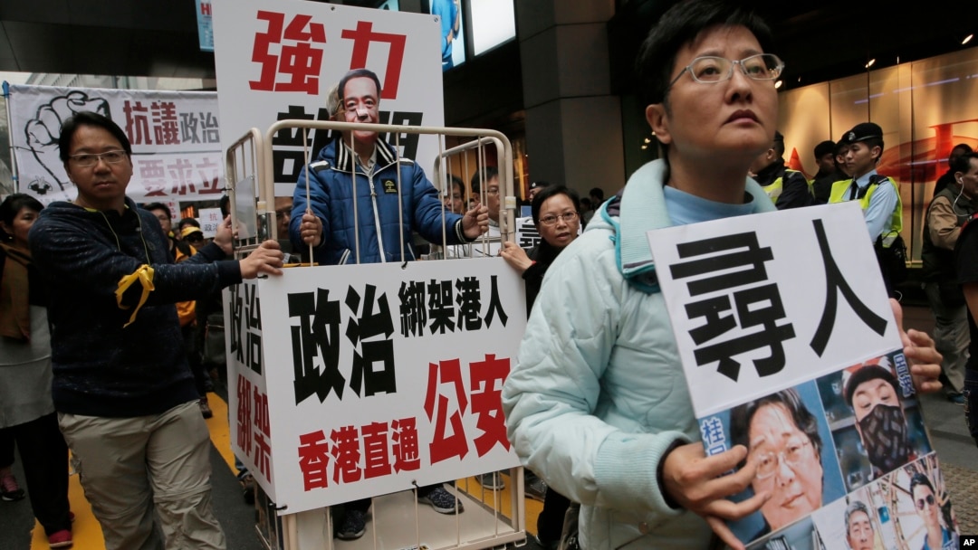FILE - A protester wearing a mask of bookseller Lee Bo stands in a cage during a protest against the disappearances of booksellers in Hong Kong, Jan. 10, 2016.