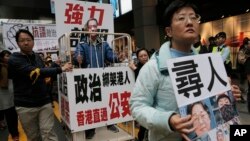 FILE - A protester wearing a mask of bookseller Lee Bo stands in a cage during a protest against the disappearances of booksellers in Hong Kong, Jan. 10, 2016.