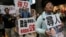 FILE - A protester wearing a mask of bookseller Lee Bo stands in a cage during a protest against the disappearances of booksellers in Hong Kong, Jan. 10, 2016.