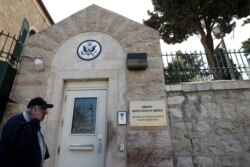 FILE - A man walks past a wall with plaques bearing the words 'Embassy United States of America' at the premises of the former US Consulate in Jerusalem, March 12, 2019.