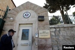 FILE - A man walks past a wall with plaques bearing the words "Embassy United States of America" at the premises of the former U.S. Consulate in Jerusalem, March 12, 2019.