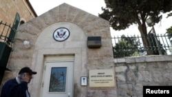 FILE - A man walks past a wall with plaques bearing the words "Embassy United States of America" at the premises of the former U.S. Consulate in Jerusalem, March 12, 2019.