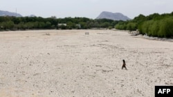 An Iranian girl walks across the Zayandeh Rud river in Isfahan, now dry because of water extraction before it reaches the city, April 11, 2018.