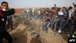 Des Palestiniens tentent de démanteler les barbelés à la frontière avec Israël, à Gaza, lors d'une manifestation, le 13 avril 2018.