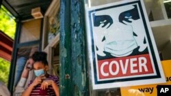 A customer exits a corner market while wearing a protective mask in the retail shopping district of the SoHo neighborhood of the Manhattan borough of New York, May 14, 2021. 