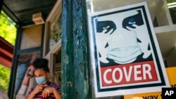 A customer exits a corner market while wearing a protective mask in the retail shopping district of the SoHo neighborhood of the Manhattan borough of New York, May 14, 2021. 