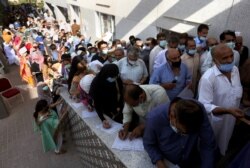 People queue to receive the first shot of the Sinopharm COVID-19 vaccine at a vaccination center in Karachi, Pakistan, May 8, 2021.