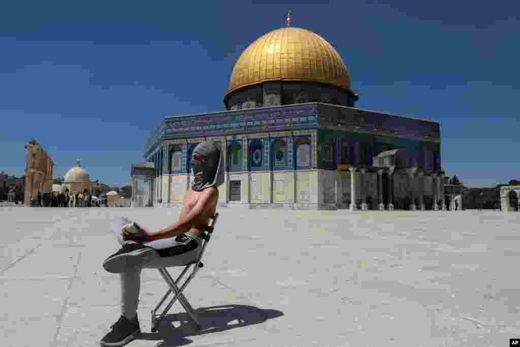 A masked Palestinian demonstrator holds a stone during clashes with Israeli security forces in front of the Dome of the Rock Mosque at the Al Aqsa Mosque compound in Jerusalem&#39;s Old City.