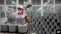 (FILE) A worker packages spools of cotton yarn at a Huafu Fashion plant in western China's Xinjiang Uyghur Autonomous Region.