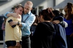 D.J. Hamburger, center in blue, a teacher at Saugus High School, comforts a student after reports of a shooting at the school, Nov. 14, 2019, in Santa Clarita, Calif.
