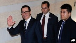 El secretario del Tesoro de EE. UU., Steven Mnuchin, a la izquierda, saluda a los periodistas cuando sale del hotel en Beijing, el miércoles 13 de febrero.