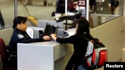 یک جوان، پاسپورت و ویزای خود را به مامور مرزی آمریکا نشان می دهد