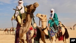 In this photo taken Feb. 18, 2018, Tuareg men ride on camels during a festival in Iferouane, Niger. 