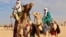 In this photo taken Feb. 18, 2018, Tuareg men ride on camels during a festival in Iferouane, Niger. 