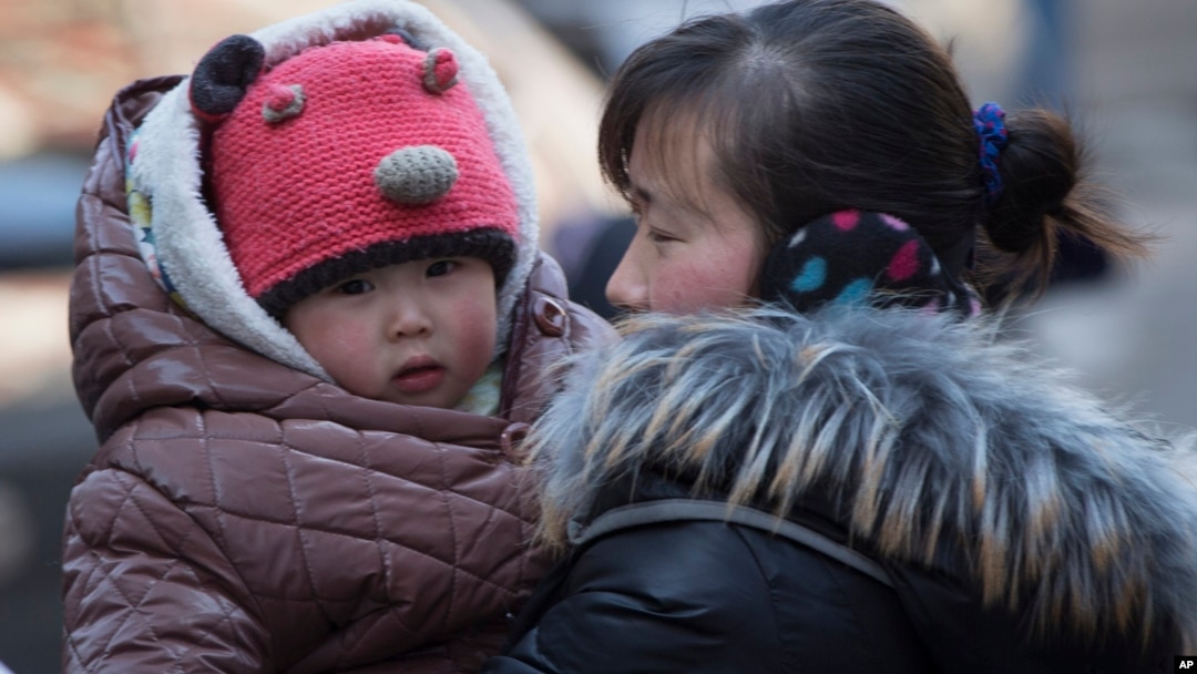 Seorang ibu menggendong anaknya di Beijing, China (foto: dok).