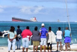 Bystanders look at the MV Wakashio bulk carrier that had run aground and from which oil was leaking, near Blue Bay Marine Park in southeast Mauritius, Aug. 6, 2020.
