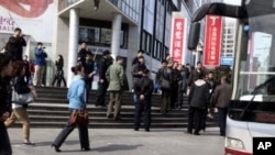 FILE - Plainclothes security personnel film as they gather to load detained worshippers onto a waiting bus near a building that leaders of the unregistered Shouwang house church had told parishioners to gather in Beijing, China, April 10, 2011.