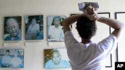 Tourist looks at portraits of former Khmer Rouge leaders Ieng Sary (R), 84, ex-foreign minister, his wife Ieng Thirith, 78, former minister of social welfare (2nd L), former prison chief Kaing Guek Eav (R), better known as Duch, former President Khieu Sam