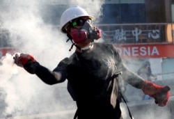 FILE - A protester throws a tear gas canister back at the police during a demonstration in support of the city-wide strike and to call for democratic reforms in Hong Kong, China, Aug. 5, 2019.