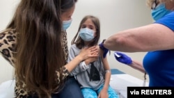 Marisol Gerardo, 9, digendong ibunya saat mendapatkan dosis kedua vaksin Pfizer selama uji klinis untuk anak-anak di Duke Health di Durham, North Carolina, AS, 12 April 2021. (Foto: via Reuters)