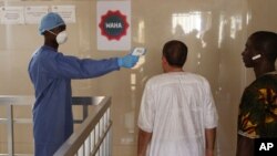 Un trabajador de la salud le toma la temperatura a varias personas para ver si tienen síntomas de Ebola. La OMS envió a varios especialistas tras confirmarse tres casos de la enfermedad que afectó a varios países africanos en 2014.