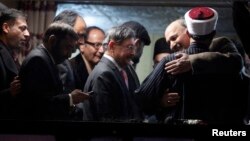 Babar Khan Ghori (R) of the Pakistan's political party Muttahida Qaumi Movement (MQM) hugs cleric and leader of Minhaj-ul-Quran Muhammad Tahirul Qadri after they reached an agreement on the fourth day of protests in Islamabad, January 17, 2013. 