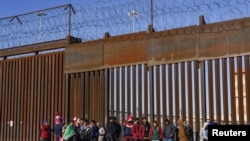Migrantes de Nicaragua, Ecuador y otras nacionalidades en una puerta en el muro fronterizo esperando ser recogidos por la Patrulla Fronteriza de Estados Unidos en El Paso, Texas, EE. UU., 4 de enero de 2023. REUTERS/Paul Ratje