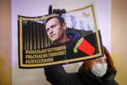 FILE - An activist holds a portrait of opposition politician Alexei Navalny during a picket in his support in St Petersburg, Russia, Dec. 22, 2020.