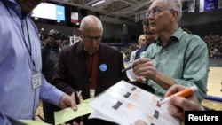 A precinct secretary and other officials look over documents at a caucus in Des Moines, Iowa, Feb. 3, 2020. Democratic Party officials had problems that led to a delay of the announcement of voting results.