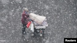 A woman pushing a stroller walks in the snow in Yantai, Shandong province, China December 4, 2017. 