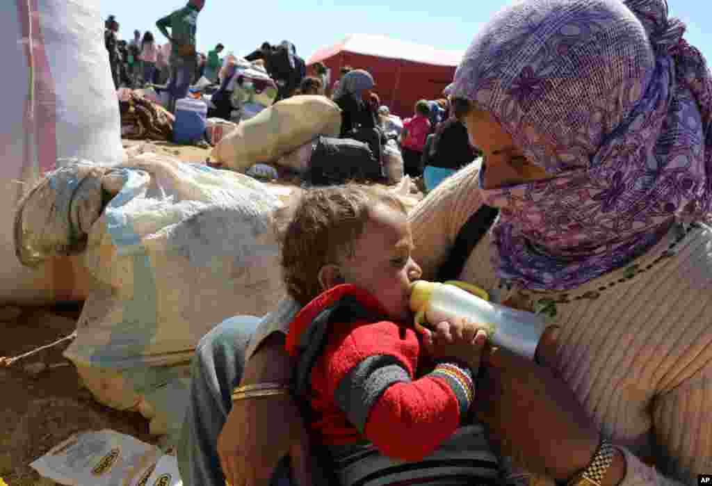 A mother feeds her baby as thousands of new Syrian refugees from Kobani arrive at the Turkey-Syria border crossing of Yumurtalik near Suruc, Turkey,&nbsp; Oct. 1, 2014. 