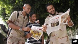 Anti-Gadhafi fighters read a newspaper where a wanted poster for Moammar Gadhafi was published in Tripoli September 1, 2011.