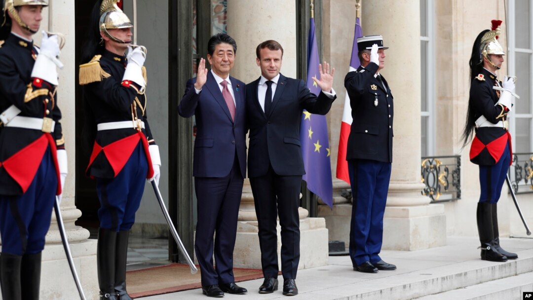 French President Emmanuel Macron, center right, and Japan's Prime Minister Shinzo Abe wave before their talks at the Elysee Palace, in Paris, April 23, 2019.