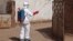 In this photo taken Friday, Nov. 14, 2014, a health worker sprays disinfectant near a mosque, after the body of a man suspected of dying from the Ebola virus was washed inside before being berried in Bamako, Mali. 