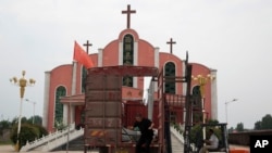 Seorang pekerja melompat dari sebuah truk yang diparkir di depan sebuah gereja dan bendera nasional Cina di dekat kota Pingdingshan di provinsi Henan China tengah, 2 Juni 2018. (Foto: dok).