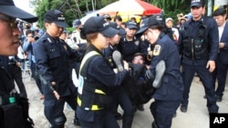 Police officers detain a Buddhist believer near the main gate of the church in Anseong, South Korea, June 11, 2014.